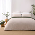 Solace Arden Reversible Duvet Cover Set shown reversed to the natural side, with coordinating natural pillowcases and a deep green fold-over edge.