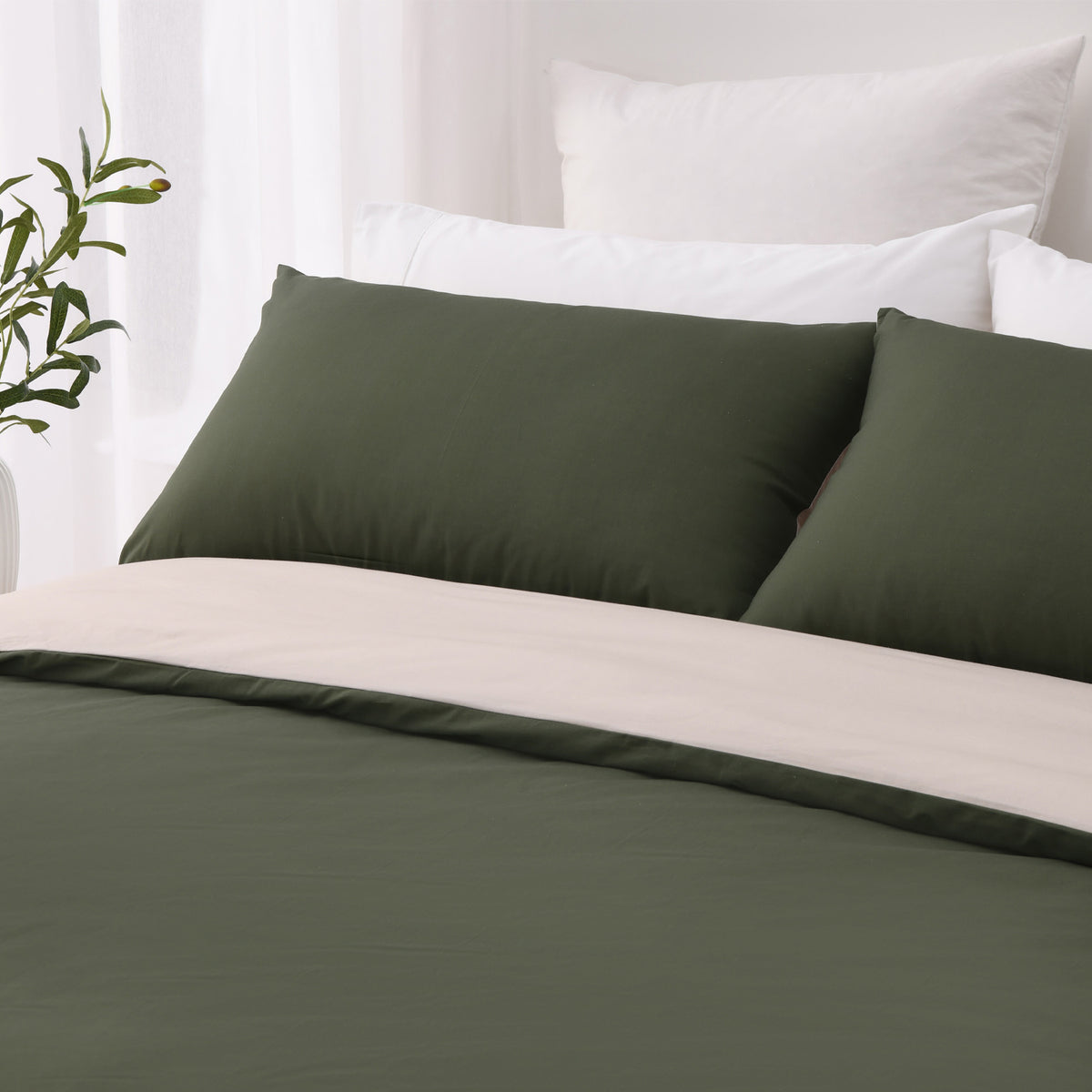 Close-up of the green side of the Solace Arden Reversible Duvet Cover Set, showing deep green pillowcases and the natural reverse folded over the duvet.
