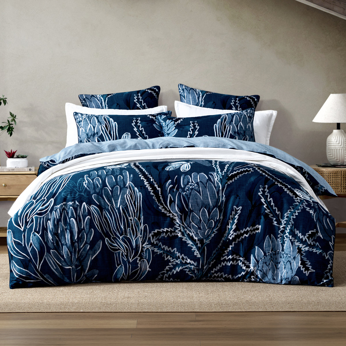 Logan & Mason Willa 100% Cotton Duvet Cover Set in Blue featuring a bold navy floral and botanical print with white and soft blue detailing, styled with coordinating pillowcases and white bedding.