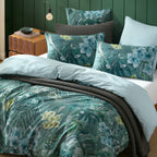 Logan & Mason Lila Surf Duvet Cover Set in Green styled with matching tropical floral pillowcases, a charcoal quilted throw and a contrasting pale blue striped reverse.