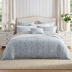 Private Collection Garden Veil Duvet Cover Set in Chambray styled on a bed with coordinating floral pillowcases, white bedding and a decorative cushion.