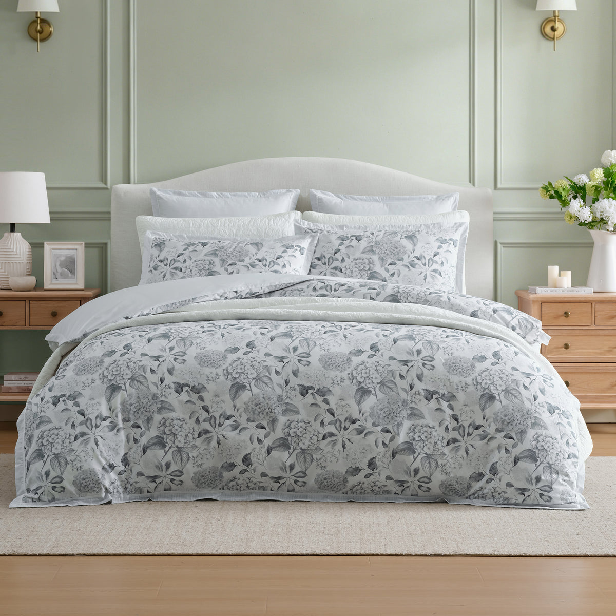 Private Collection Hydrangea 100% Cotton Duvet Cover Set featuring a soft grey and white hydrangea floral design, styled with coordinating pillowcases and white bedding in an elegant bedroom.