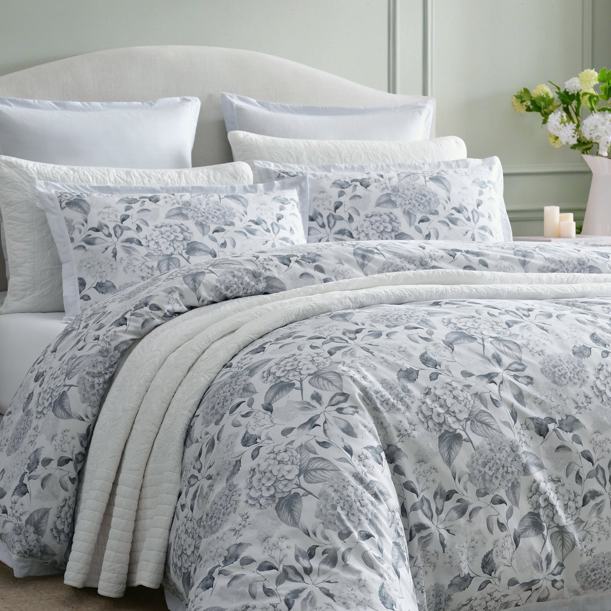 Private Collection Hydrangea Duvet Cover Set styled on a bed with matching floral pillowcases, white quilted bedding and a soft grey botanical design.
