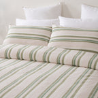 Marlo Neve Cotton Duvet Cover Set styled on a bed, featuring soft green and sage stripes on a natural white background with coordinating pillowcases.