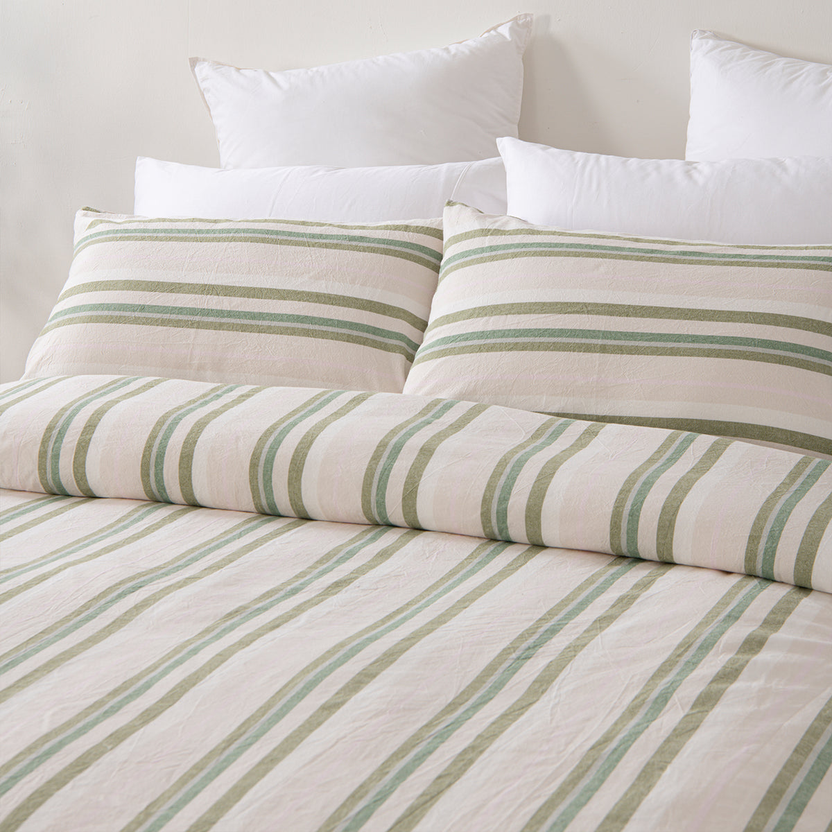 Marlo Neve Cotton Duvet Cover Set styled on a bed, featuring soft green and sage stripes on a natural white background with coordinating pillowcases.
