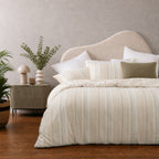 Multi-coloured striped jacquard duvet cover set styled on a bed with matching pillowcases in a warm, contemporary bedroom.