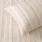 Close-up of the duvet cover fabric showing the woven cream, beige and fine grey striped jacquard texture.
