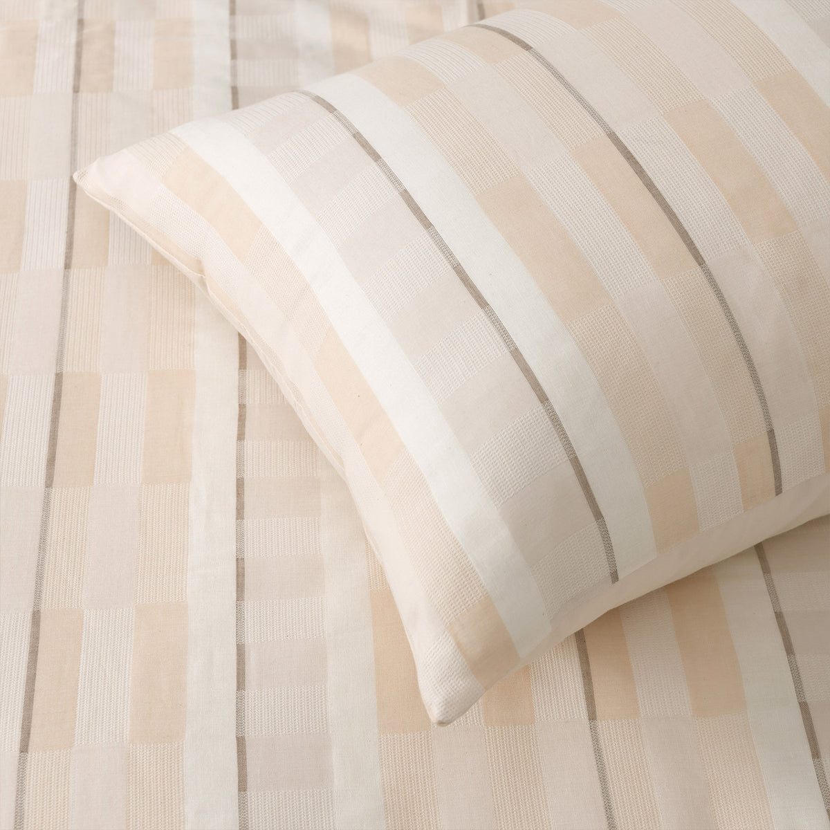 Close-up of the duvet cover fabric showing the woven cream, beige and fine grey striped jacquard texture.