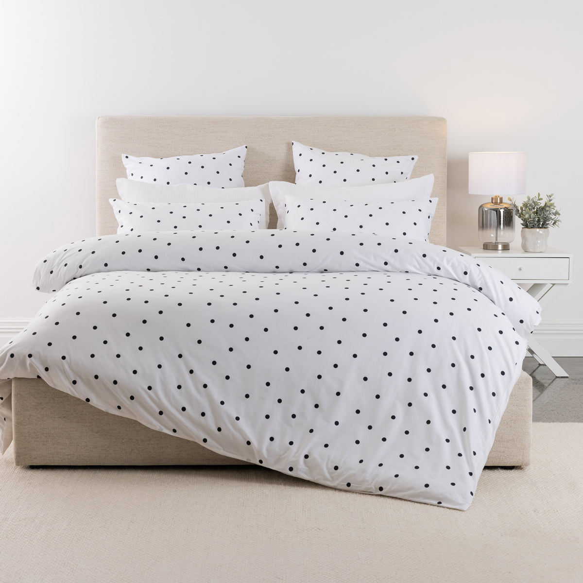 Pure & Simple Monroe Cotton Duvet Cover Set in white with black polka dots, styled on a bed with coordinating pillowcases against a neutral upholstered headboard.