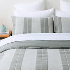 Baker St. Linen Calvin Cotton Jacquard Duvet Cover Set displayed on a bed with matching striped pillowcases, white pillows and a folded grey reverse.