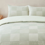 Close-up of the Baker St. Linen Zane Cotton Jacquard Duvet Cover Set in Sage, featuring a subtle check pattern with textured horizontal detailing and matching pillowcases.