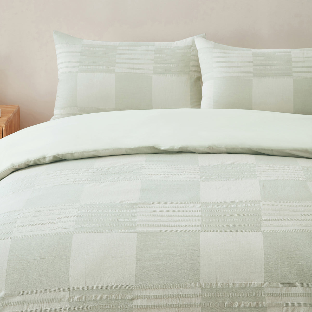 Close-up of the Baker St. Linen Zane Cotton Jacquard Duvet Cover Set in Sage, featuring a subtle check pattern with textured horizontal detailing and matching pillowcases.