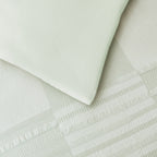 Close-up of the Baker St. Linen Zane Duvet Cover Set in Sage, showing the smooth reverse fabric alongside the textured jacquard front.