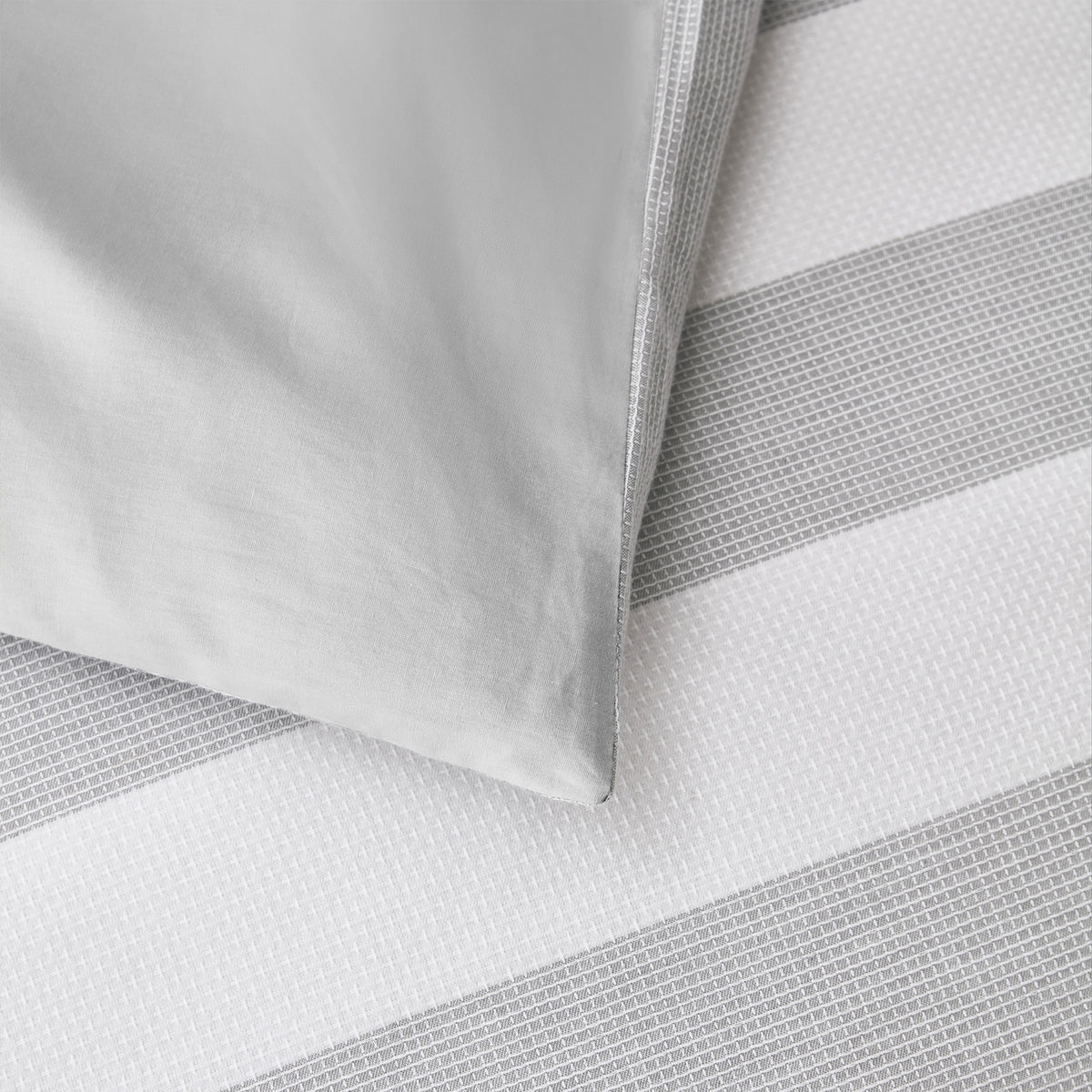 Baker St. Linen Samson Cotton Jacquard Duvet Cover Set in Grey styled on a bed with matching pillowcases, highlighting its grey and white striped design.