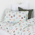 Animal print kids duvet cover set styled with a sage green pillow on a white bed.