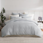 A beautifully styled bed dressed in soft ice blue bedding creates a fresh, calming look, layered with coordinating cushions and crisp white pinstripe accents.