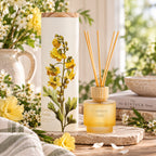 A frosted glass with reeds diffuser shown in a styled indoor setting with flowers.