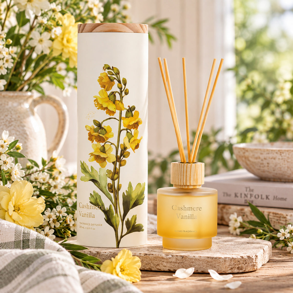 A frosted glass with reeds diffuser shown in a styled indoor setting with flowers.