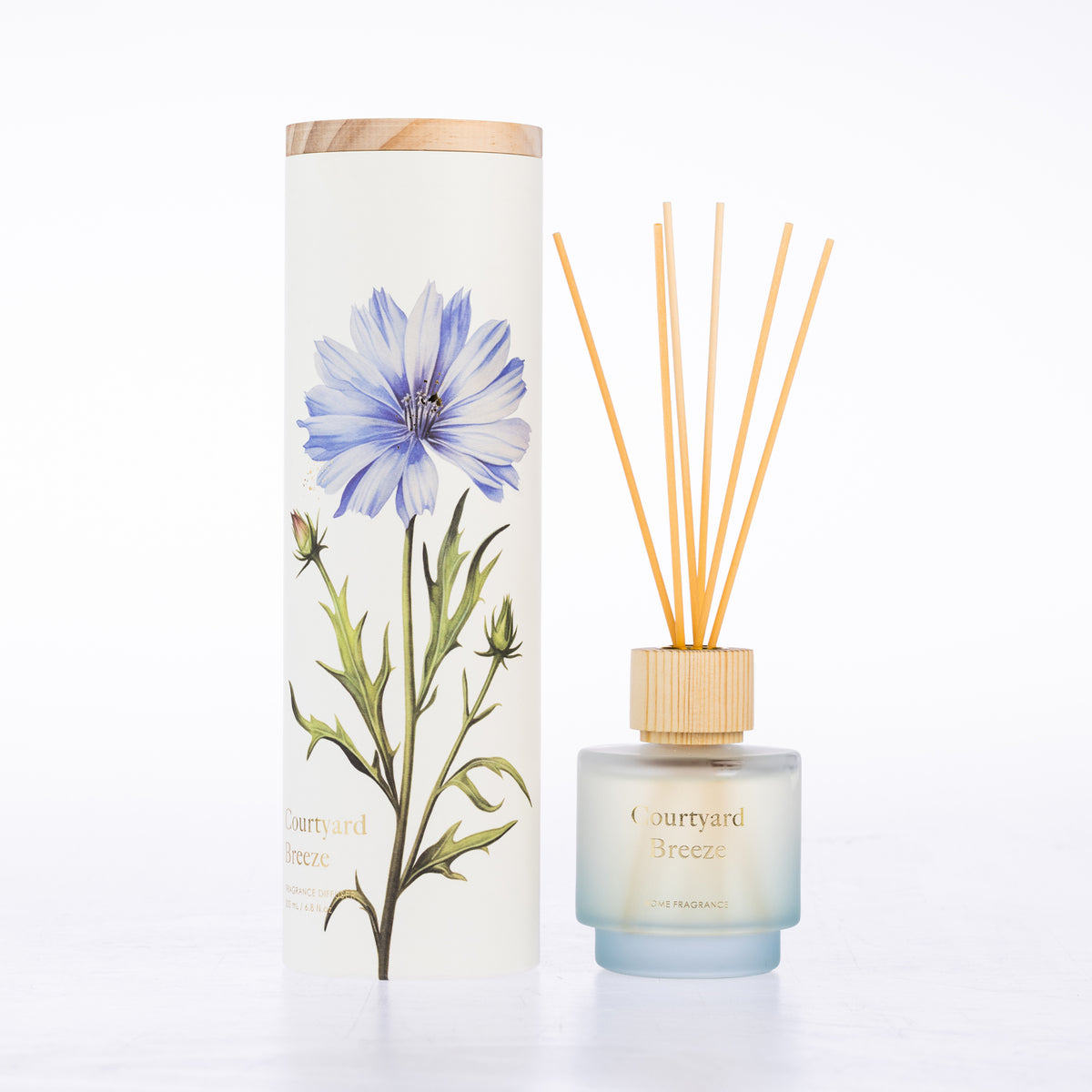 A frosted glass with reeds diffuser beside its matching cylindrical box packaging.