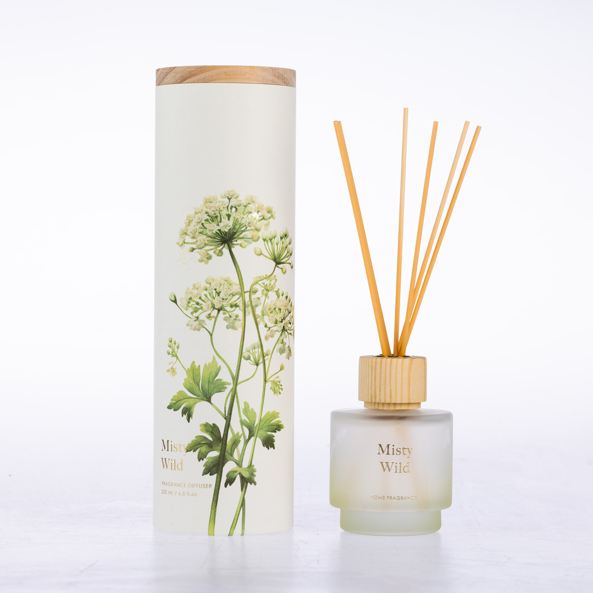 A frosted glass with reeds diffuser beside its matching cylindrical box packaging.