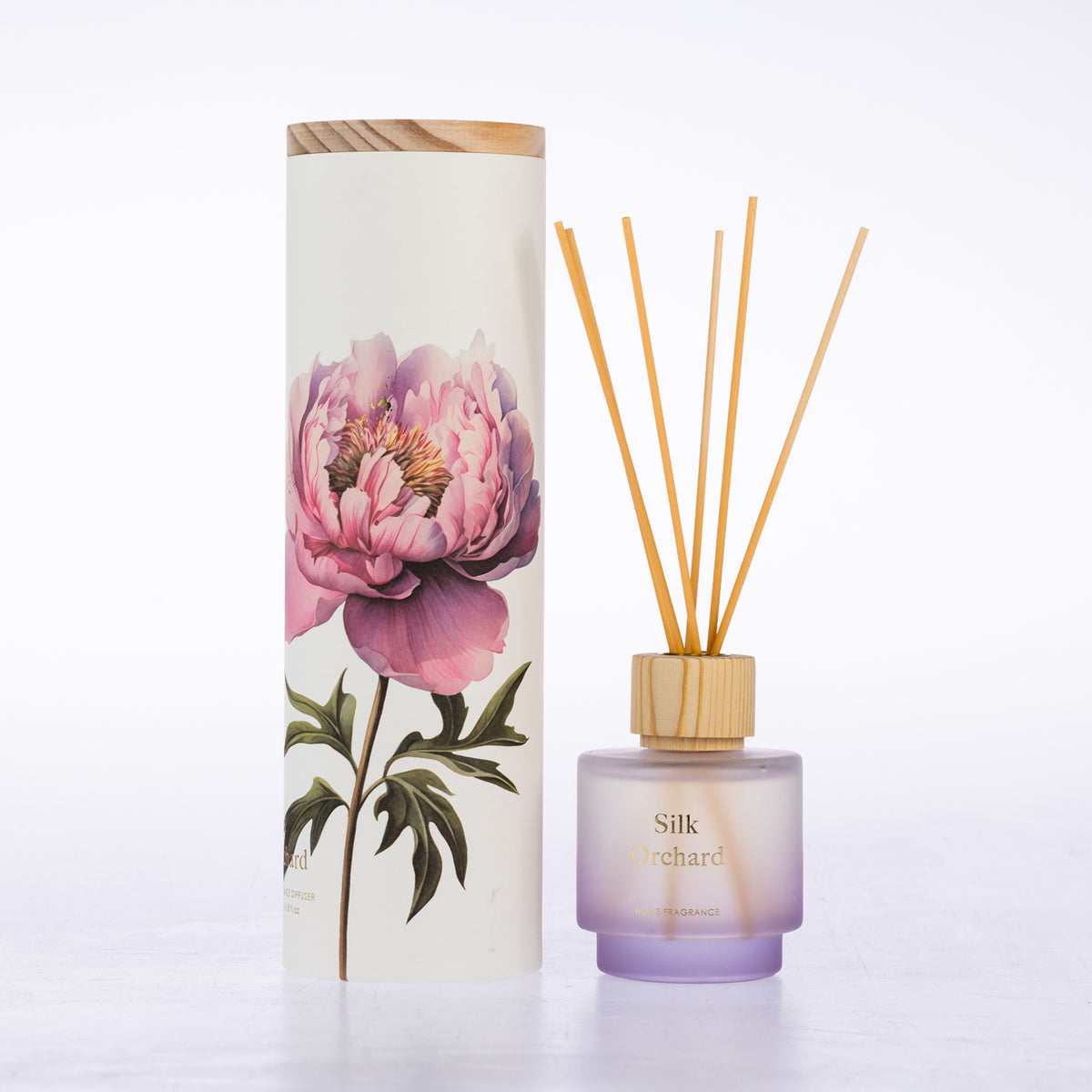 A frosted glass with reeds diffuser beside its matching cylindrical box packaging.