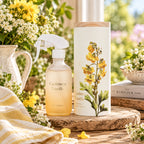 A frosted glass room spray shown in a styled indoor setting with flowers.