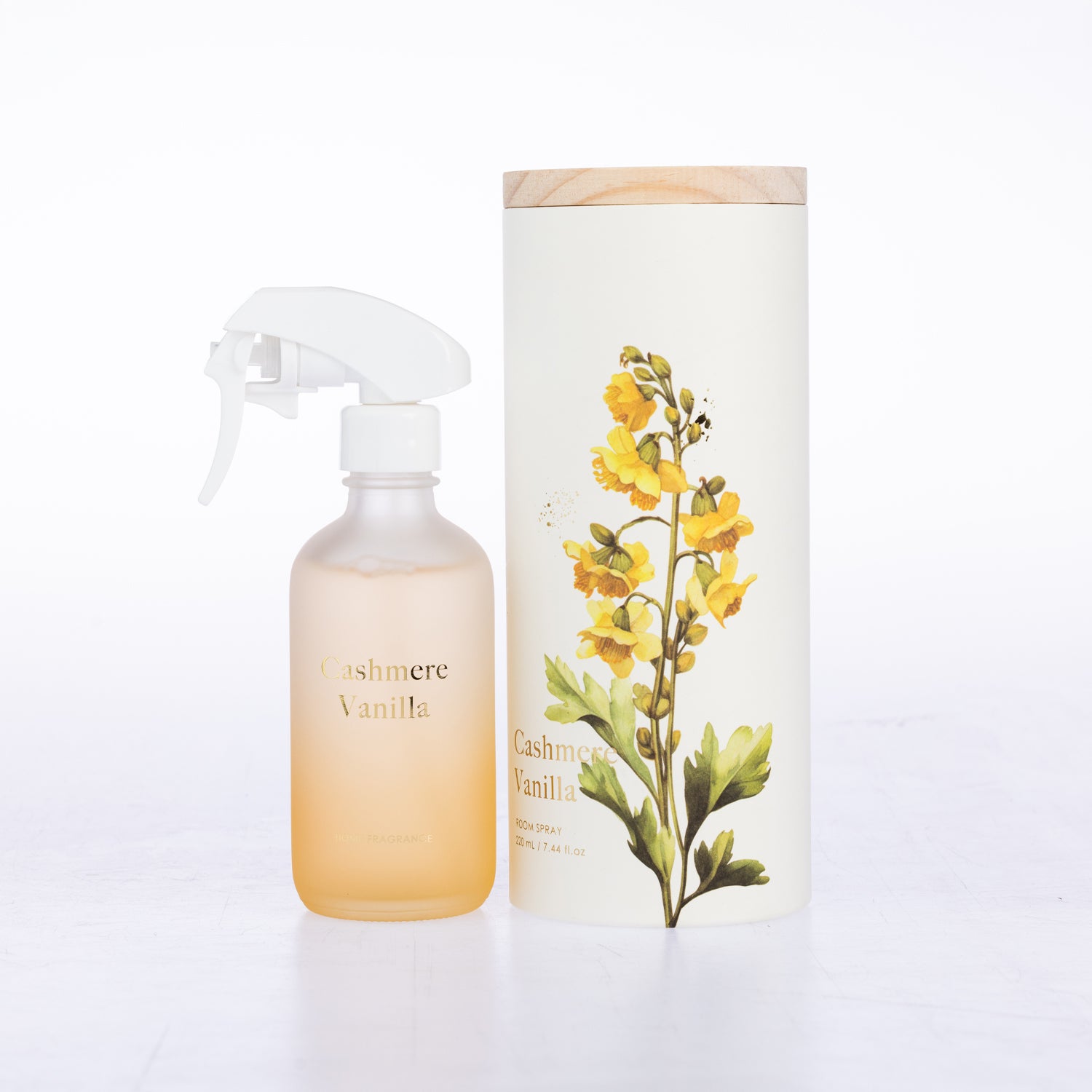 A frosted glass room spray beside its matching cylindrical box packaging.