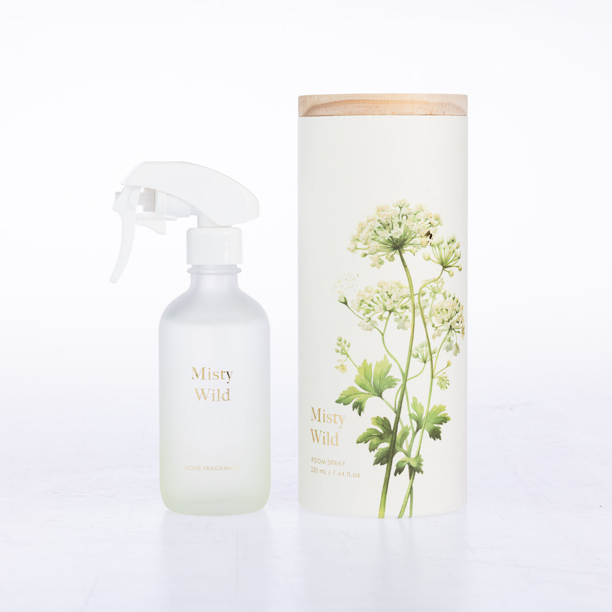 A frosted glass room spray beside its matching cylindrical box packaging.
