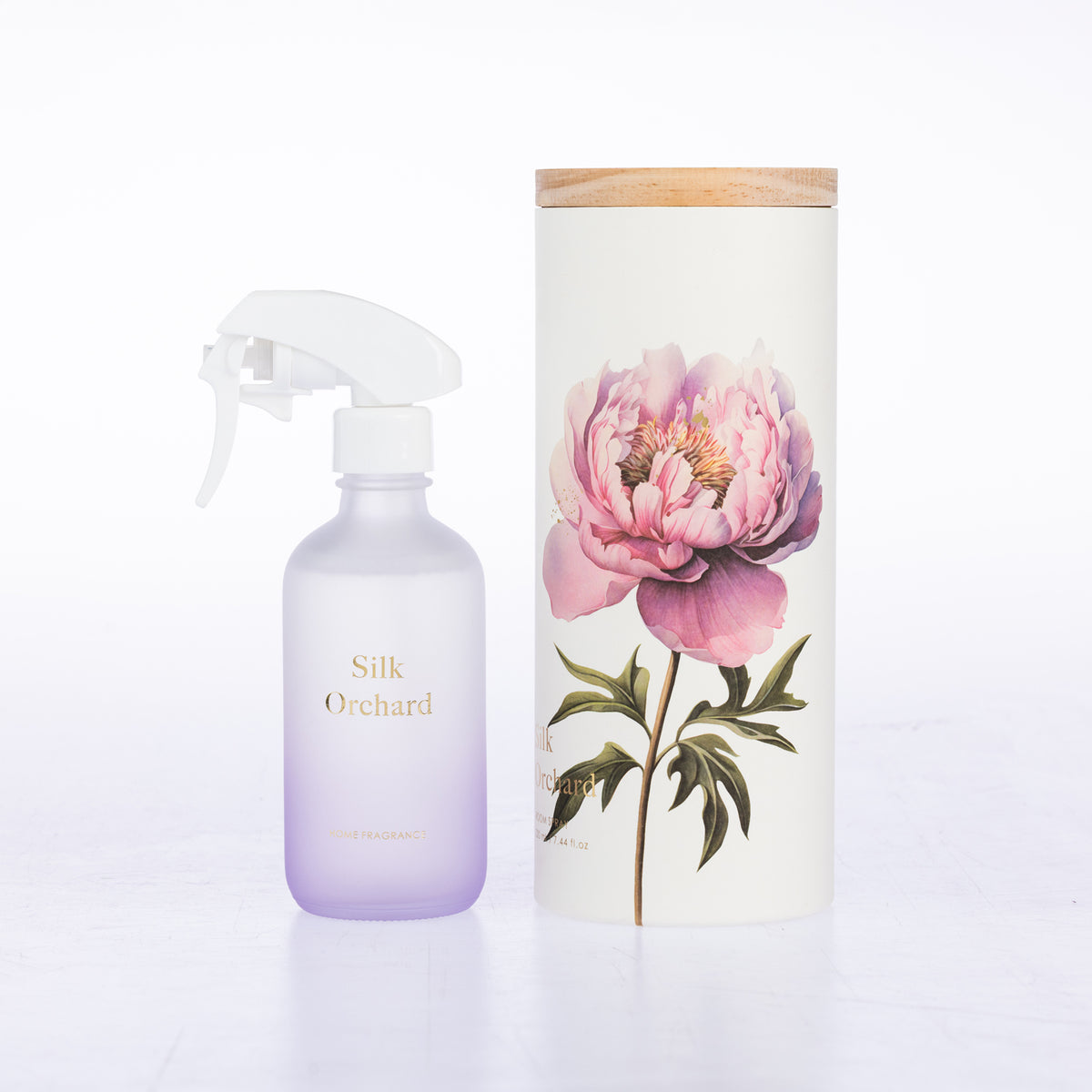 A frosted glass room spray beside its matching cylindrical box packaging.
