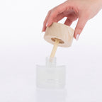 Design Republique Bamboo Jasmine Orion Reedless Diffuser shown open with the natural wood-look lid and bamboo diffuser insert being lifted from the frosted glass vessel.
