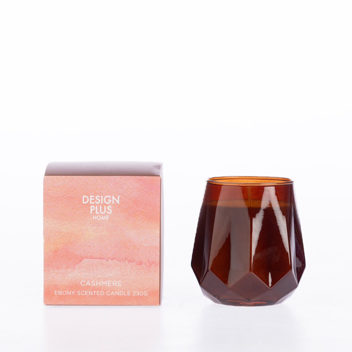 Design Plus Home Cashmere Ebony Scented Candle 230g in an amber faceted glass vessel, displayed beside its peach-toned packaging.