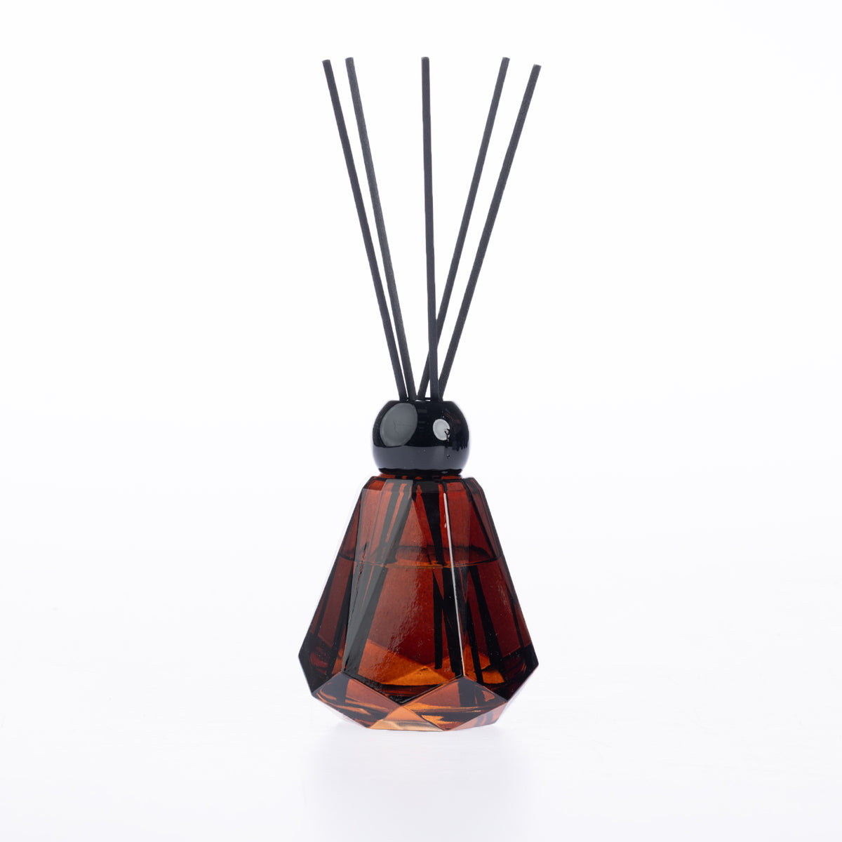 Design Plus Home Cashmere Ebony Diffuser 180ml in an amber faceted glass vessel with black reed sticks and a glossy black cap.