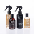 Four Design Plus fragrance products with black spray and pump caps arranged on a white background: an ivory linen spray, a jasmine room spray in a dark bottle, a morning vale linen spray in a tall black bottle, and a bamboo room spray in a clear bottle with amber liquid.