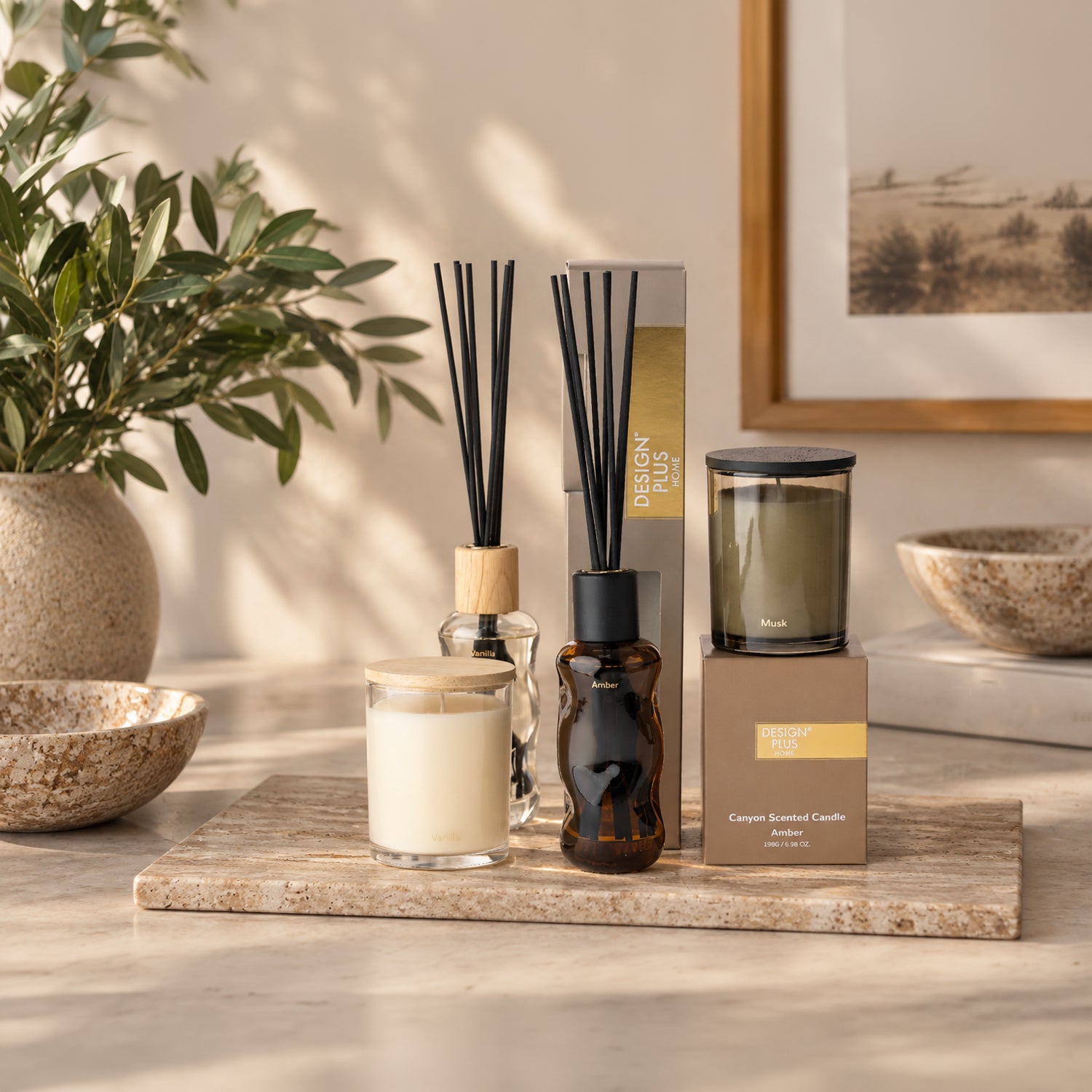 A styled home fragrance range on a stone tray featuring reed diffusers and glass jar candles.