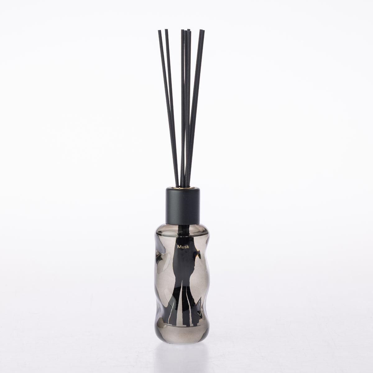 A reed diffuser bottle made of smoky translucent glass with a matte black cap and several black reeds, shown on a clean white background.