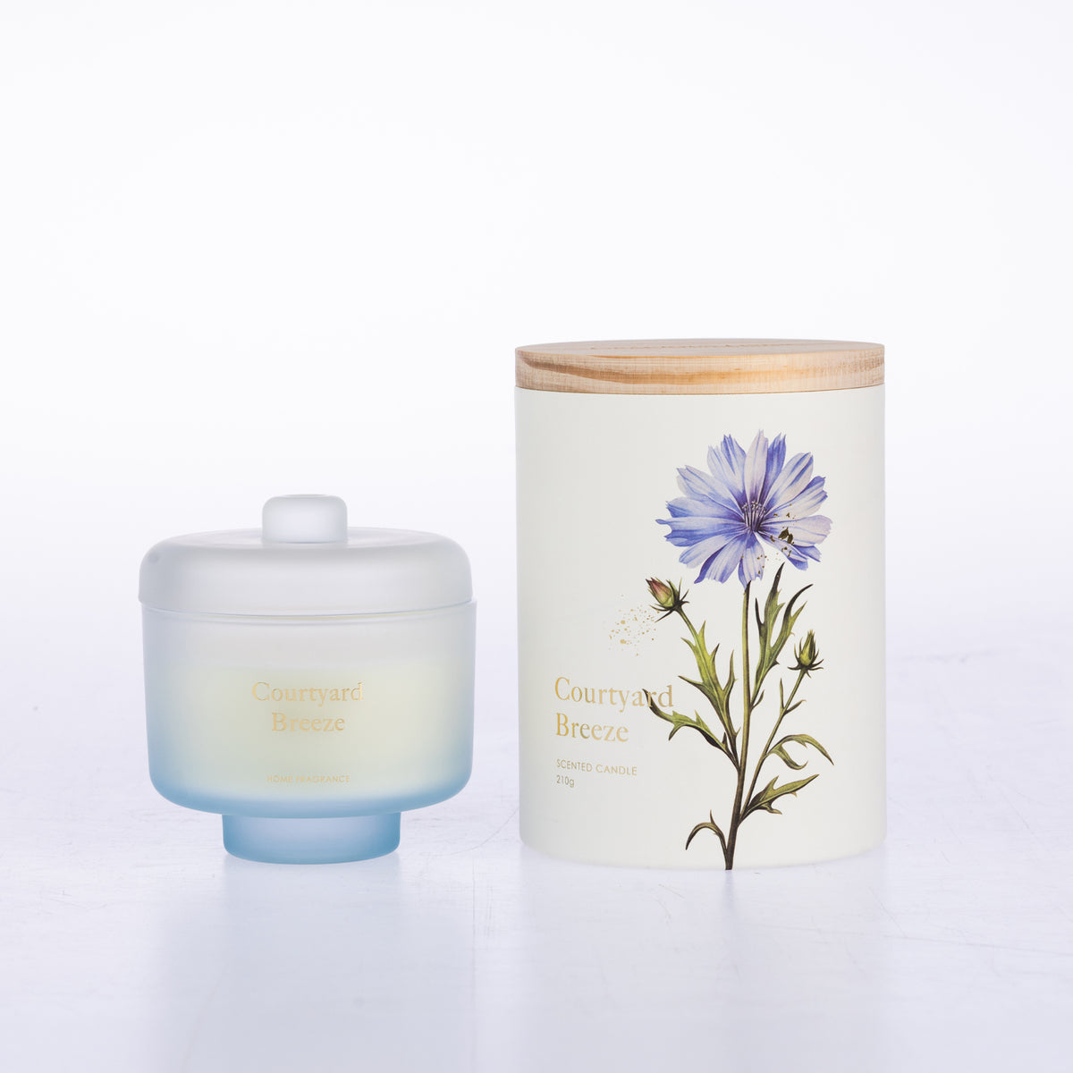 A frosted glass jar candle sits beside its matching cylindrical box packaging.