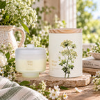A frosted jar candle shown in a styled indoor setting with flowers.