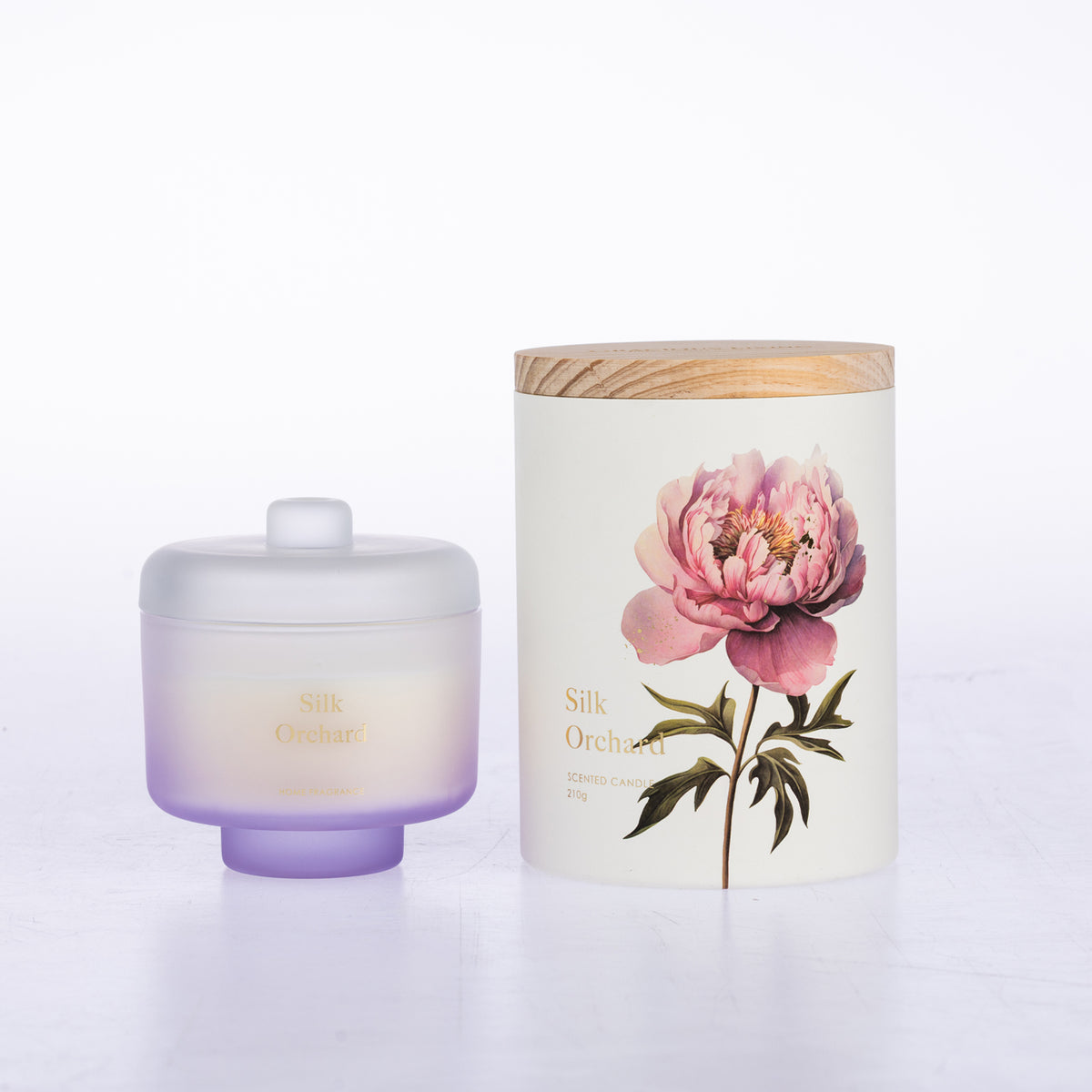 A frosted glass jar candle sits beside its matching cylindrical box packaging.