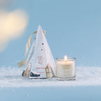 Christmas Wishes Mini Candle in Gift Box 50g Spiced Plum – Spiced Plum scented soy candle in a clear glass vessel, displayed beside its pale blue cone-shaped Christmas gift box featuring festive village illustrations.
