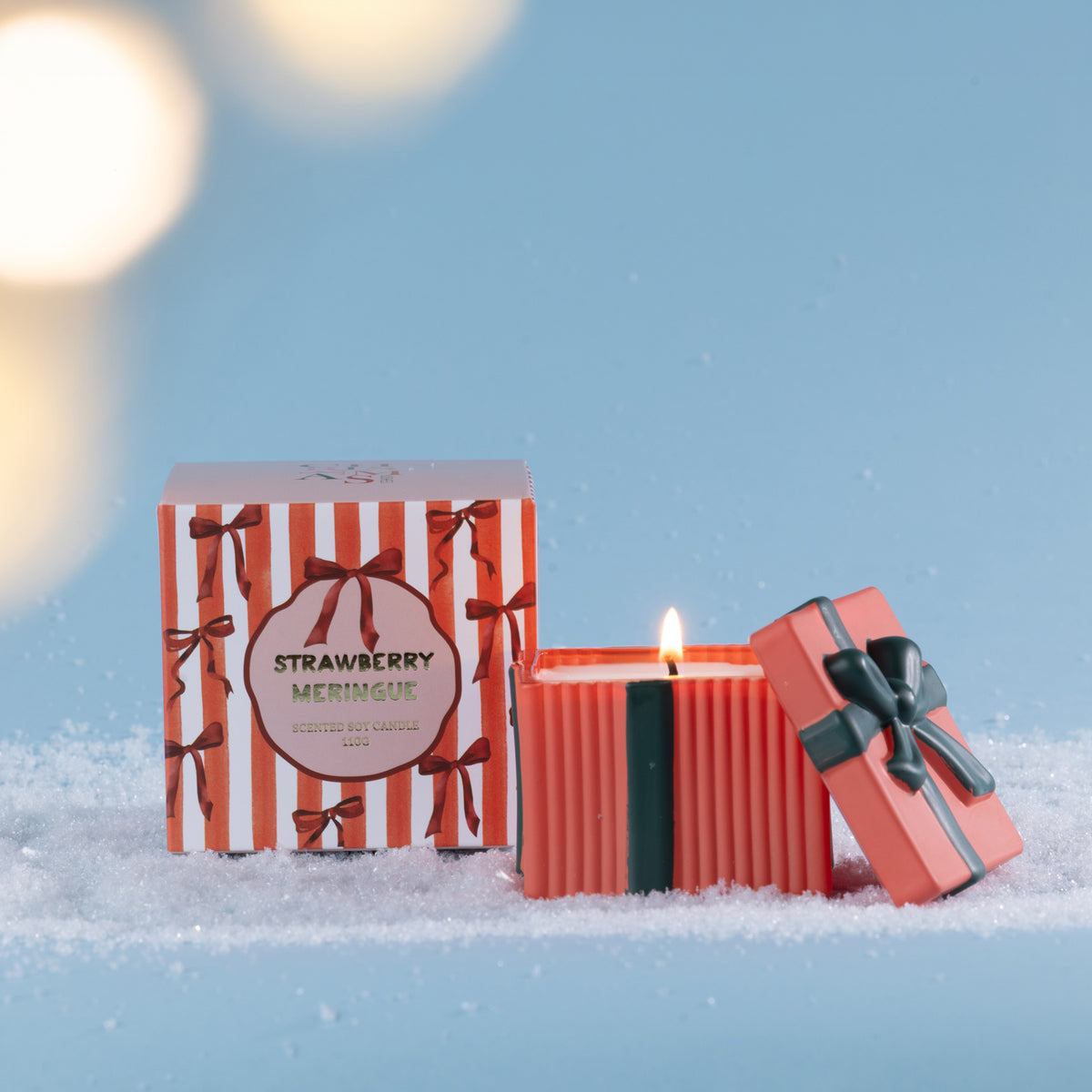 Christmas Wishes Bow Candle in a Box 110g Strawberry Meringue – Coral ribbed scented soy candle with dark green ribbon detailing and decorative bow lid, displayed beside its coordinating striped Strawberry Meringue gift box.