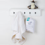 Cot duvet inner hanging on a wall hook beside its packaged product.