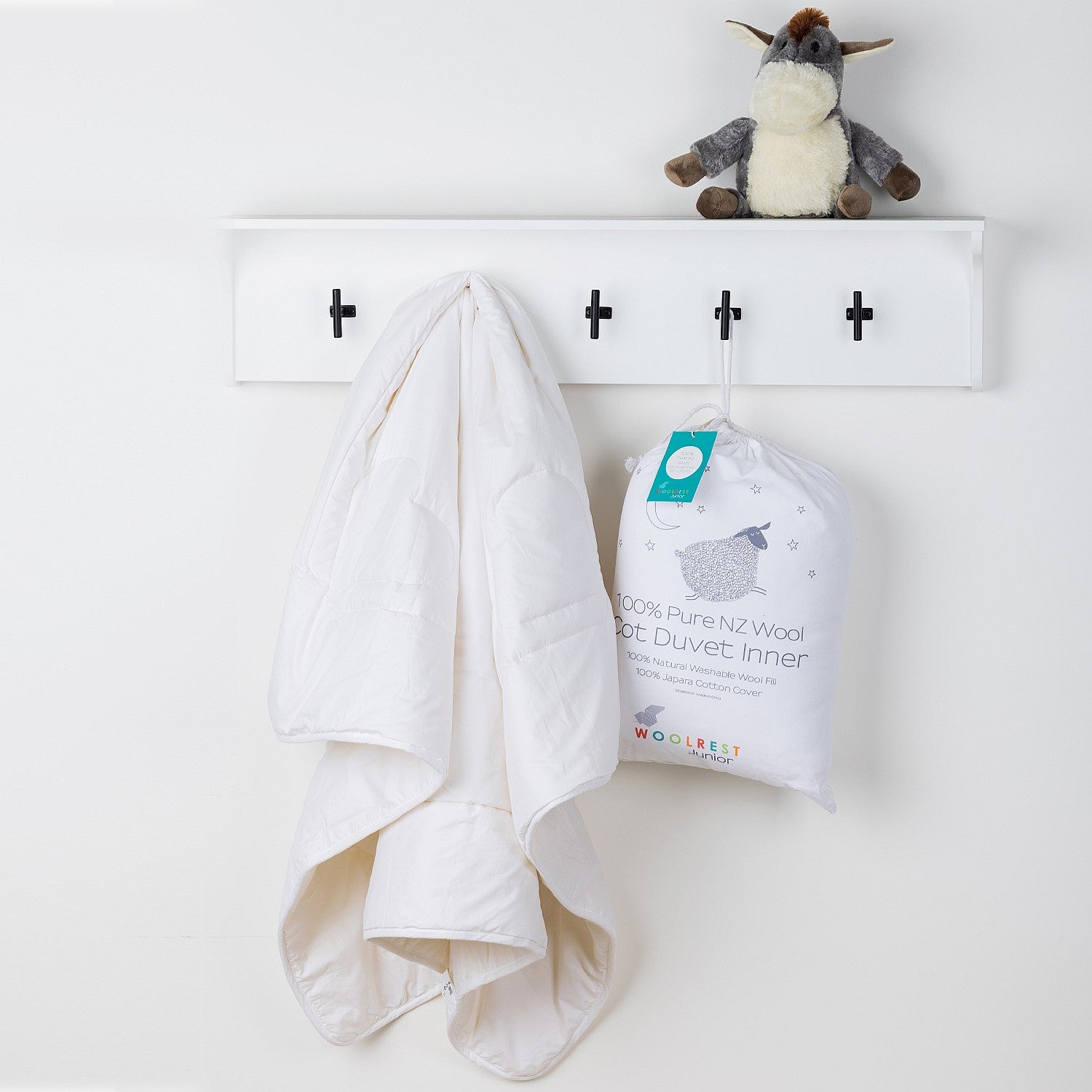 Cot duvet inner hanging on a wall hook beside its packaged product.