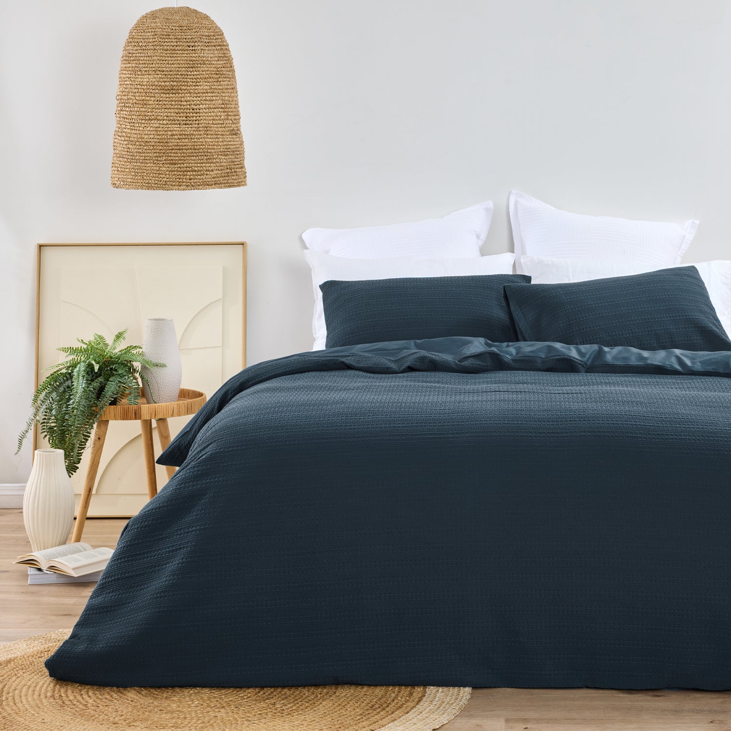 Design Plus August Cotton Waffle Duvet Cover Set in Diesel Blue styled in a contemporary bedroom with matching waffle weave pillowcases, white layered pillows, natural timber furniture, woven lighting, and botanical décor.