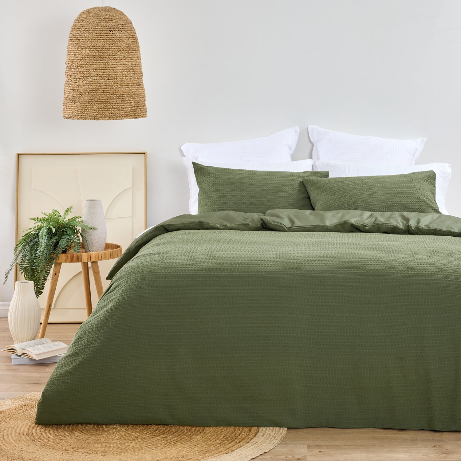 Design Plus August Cotton Waffle Duvet Cover Set in Green styled in a contemporary bedroom with matching waffle weave pillowcases, white layered pillows, natural timber furniture, woven lighting, and botanical décor.