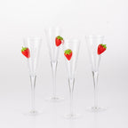 Four clear champagne flutes with raised strawberry embellishments arranged together against a white background.
