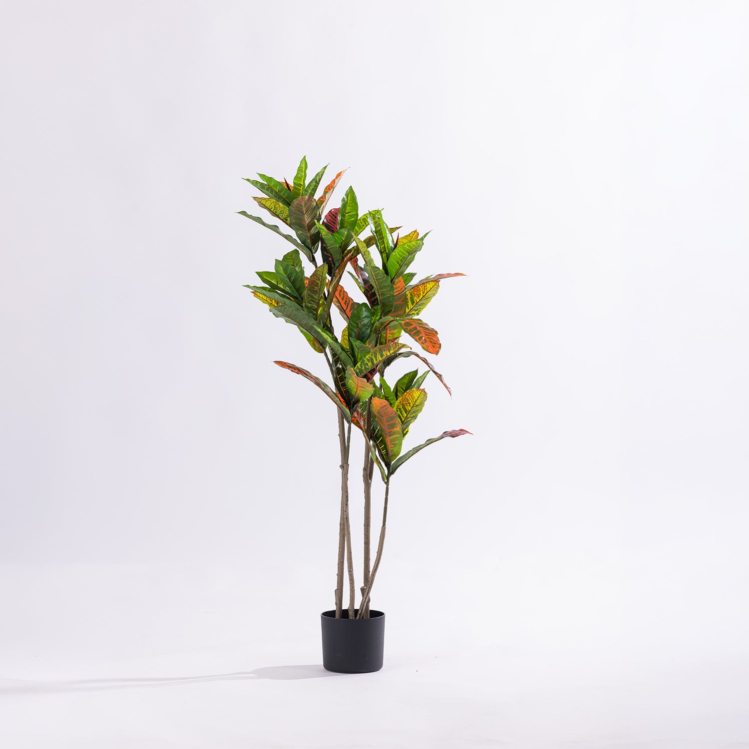 Artificial 115cm codiaeum tree with vibrant green, yellow, orange and red variegated foliage displayed in a black nursery pot.