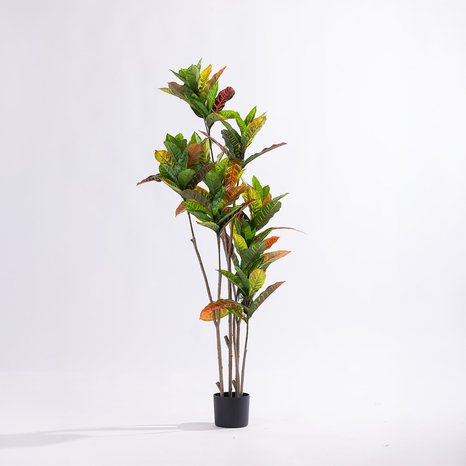 Artificial 145cm codiaeum tree with vibrant green, yellow, orange and red variegated foliage displayed in a black nursery pot.