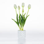 Artificial white tulip arrangement with realistic blooms and green foliage displayed in a white speckled pot.
