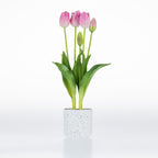 Artificial pink tulip arrangement with realistic blooms and green foliage displayed in a white speckled pot.