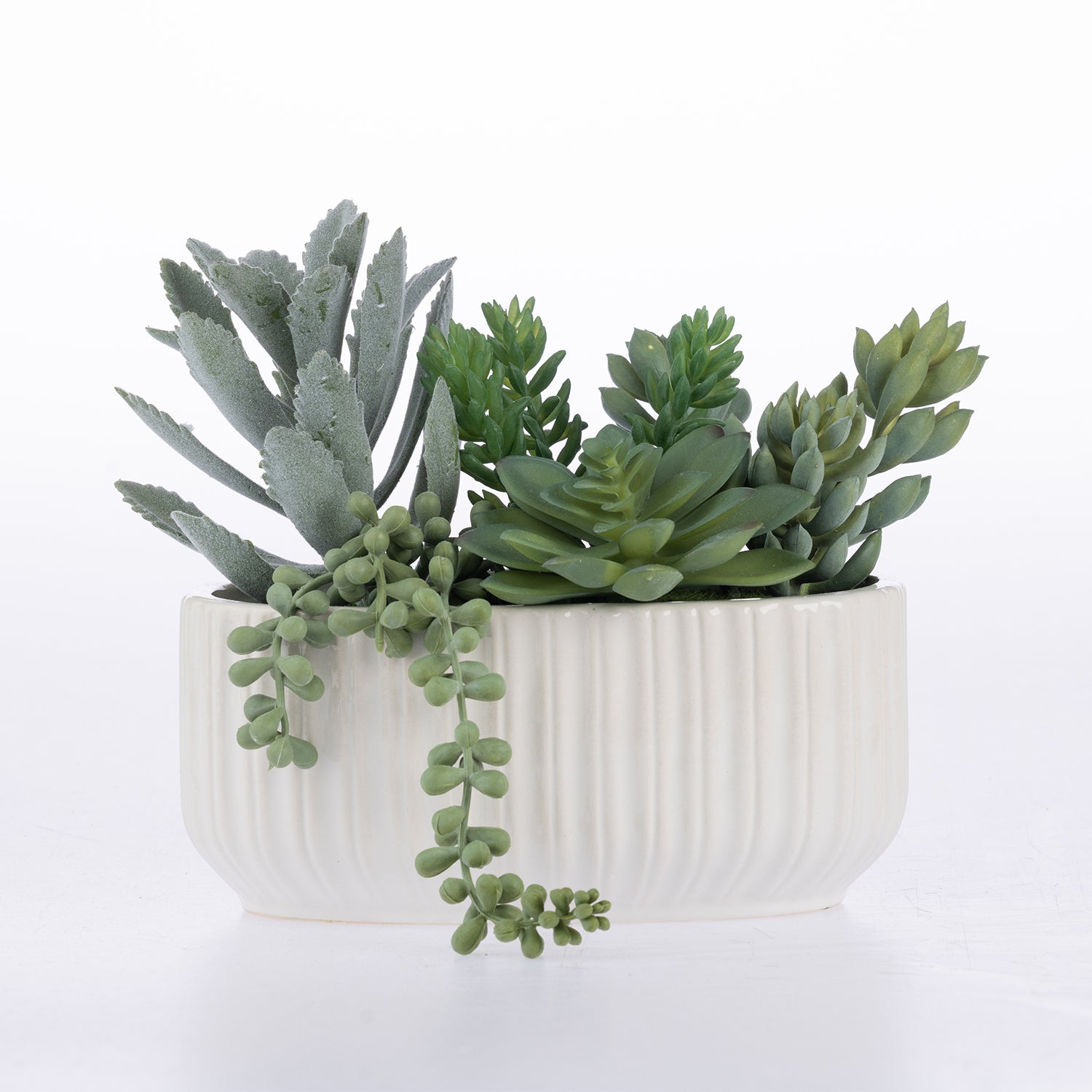 A faux succulent arrangement in a white ribbed ceramic pot, photographed on a clean white background.